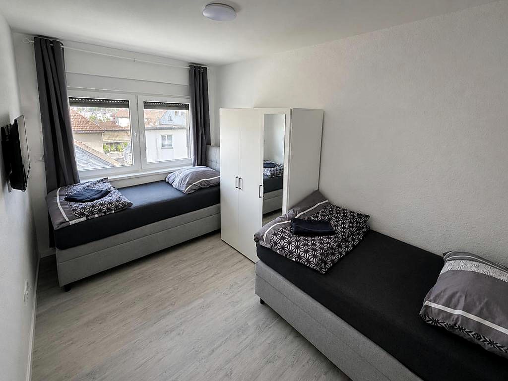Zimmer mit zwei Betten, Kleiderschrank und Blick über die Dächer